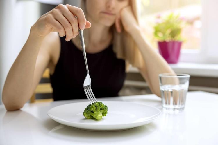 chica deprimida ante un plato escaso de comida