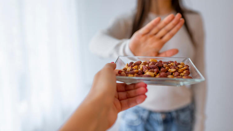 chica rechazando un plato de frutos secos