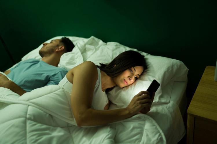 mujer esquivando a su pareja en la cama